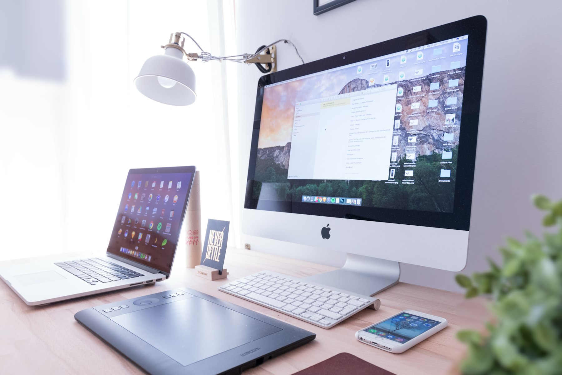 A designer's workspace with a large display, laptop, keyboard and drawing tablet